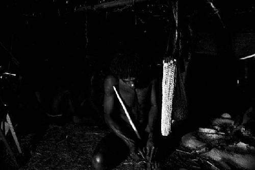 Weaklekek making a cigarette near his fireplace in his honai