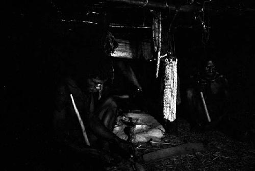 Weaklekek making a cigarette near his fireplace in his honai