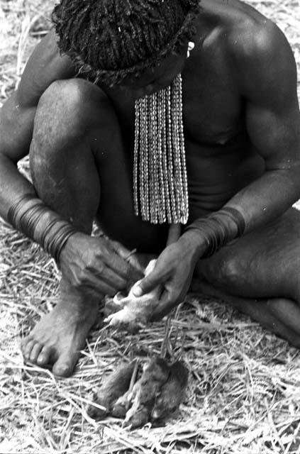 A man taking the guts out of mice, which will be cooked and eaten