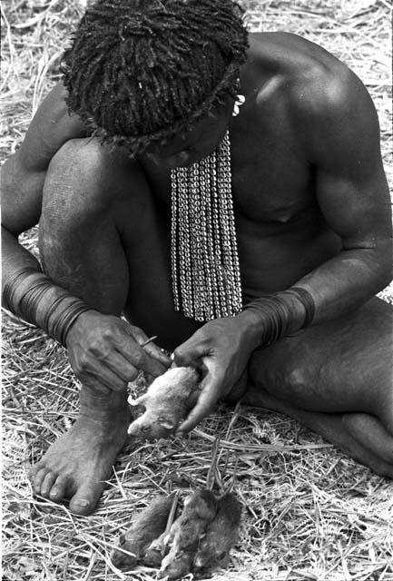 A man taking the guts out of mice, which will be cooked and eaten