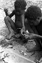 2 boys eviscerating rats on a banana leaf