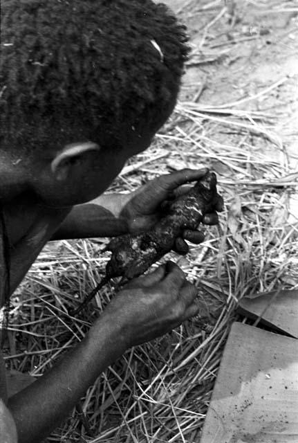 Young boy with a charred rat in his hand