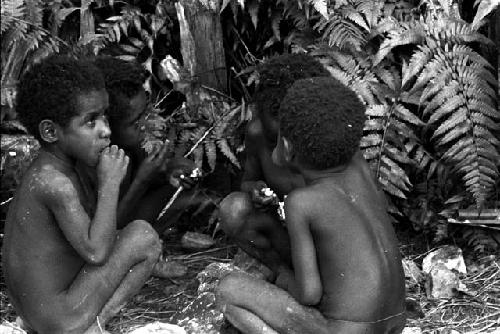 Young boys eating parts of cooked meat