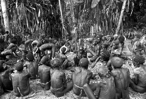 Group of men seated waiting for the contents of the hakse to be distributed