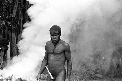 Ouside in the back sili Tegé Warek stands; clouds of steam from the haksé coming up behind him