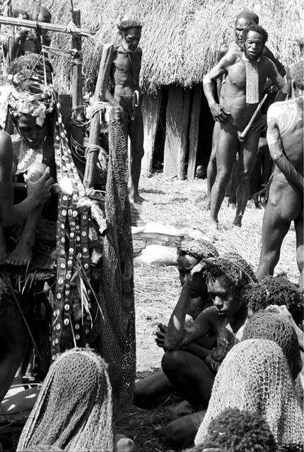 Molaré is adjusting Waeke's knees; another woman is fixing the sus that hang from the pia