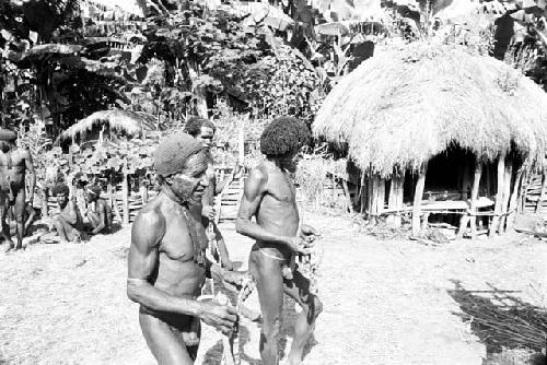 Men bringing the cowrie shells to put on the corpse