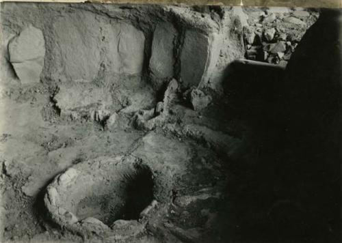 Interior of excavated building with small round pit in center