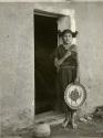 Hopi woman standing in a doorway and holding a basket