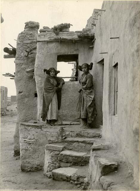 Two Hopi women standing in front of a window