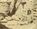 Hopi man sitting, with several pots next to him