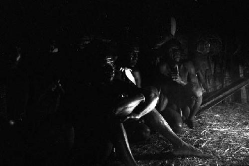 Men seated around the wall of the honai at Lokoparek