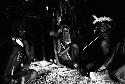 3 men seated in honai; Michael Rockefeller's feet and legs in right hand half of frame
