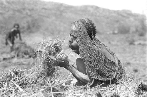 A woman trying to get some cinders in a grass bundle started to burn - to burn trash in the fields