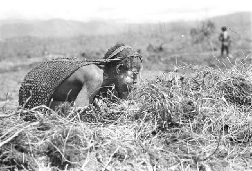 A woman trying to get some cinders in a grass bundle started to burn - to burn trash in the fields