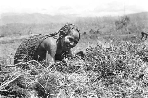 A woman trying to get some cinders in a grass bundle started to burn - to burn trash in the fields