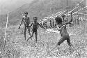 Children beginning to play sikoko wasin; school building going up in the background