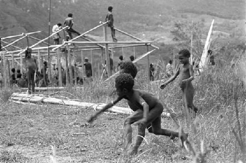 Children beginning to play sikoko wasin; school building going up in the background