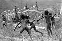 Children beginning to play sikoko wasin; school building going up in the background