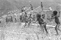 Children beginning to play sikoko wasin; school building going up in the background