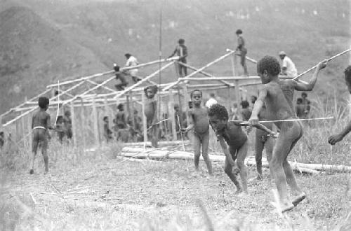 Children beginning to play sikoko wasin; school building going up in the background