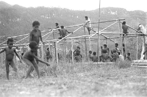 Children beginning to play sikoko wasin; school building going up in the background