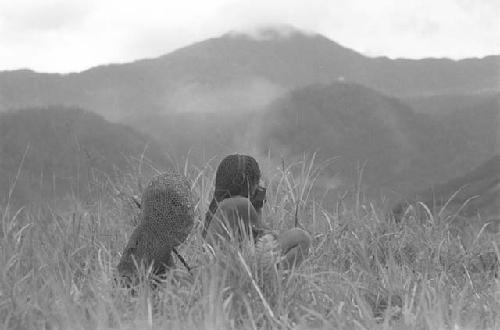 2 women sitting and watching; at a distance; school being built