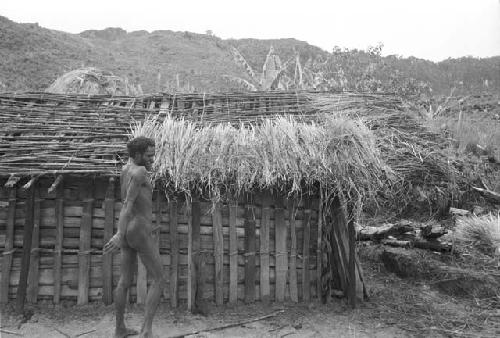 Apeori and another man begin the thatching on the roof of the new hunu in Abukulmo