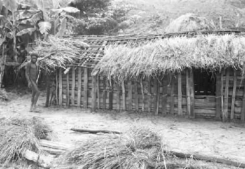 Apeori and another man begin the thatching on the roof of the new hunu in Abukulmo