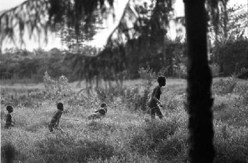 Thru the trees at the edge of forest of Homoak at boys playing weem yele