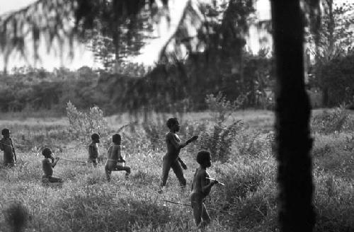 Thru the trees at the edge of forest of Homoak at boys playing weem yele