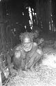 Old man in a hunu; sitting on his haunches