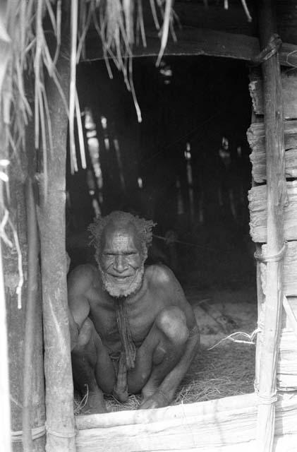 Old man in a hunu; sitting on his haunches