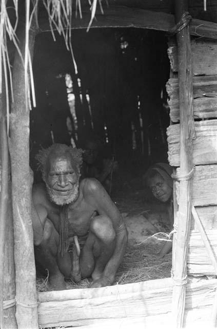 Old man in a hunu; sitting on his haunches