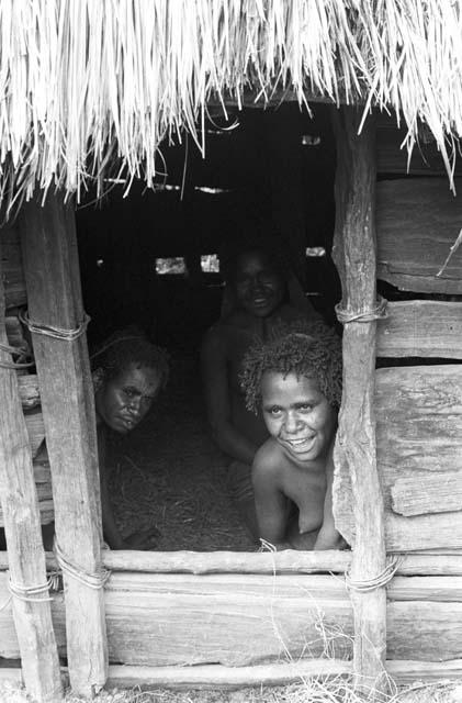 Two women look out of doorway of hunu