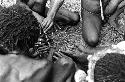 Men being 'cleaned'; this is Sue samilek; feather is being brushed over the hands of men who have something to do with this dead body