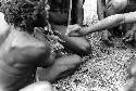 Men being 'cleaned'; this is Sue samilek; feather is being brushed over the hands of men who have something to do with this dead body