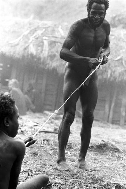 Etamugwi stands up to make the bow string