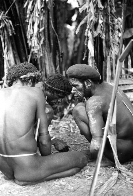 Outside of the honai, Weaklekek and two other men talking