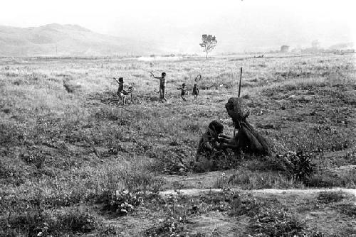 2 women sit on the salt trail; boys in the background playing sikoko wasin