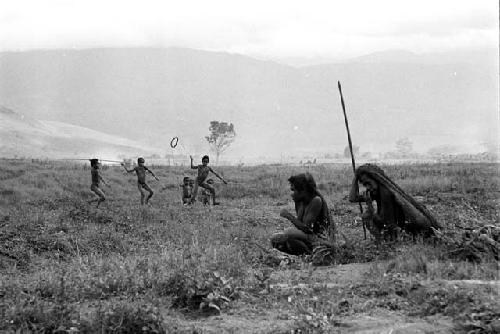 2 women sit on the salt trail; boys in the background playing sikoko wasin