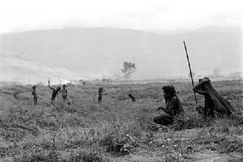 2 women sit on the salt trail; boys in the background playing sikoko wasin