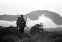 Woman walking home towards the south; child and nets full of hiperi on her back