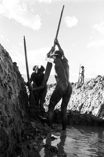 Two men working in deep garden ditch