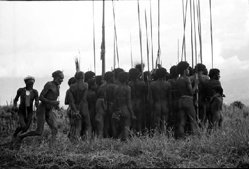 Men around dead birds; men running in a circle also around the group