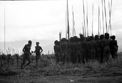 Men around dead birds; men running in a circle also around the group