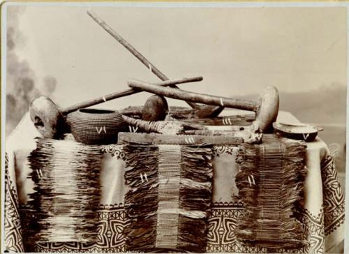 Basket, seashell, three long objects on Indian blankets