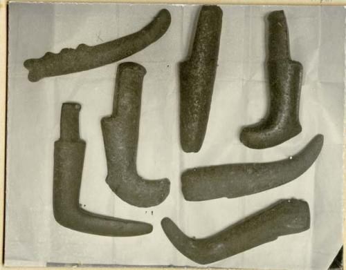 Seven stone implements, five with curved ends, probably used as clubs