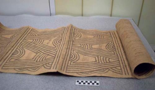 Bark cloth textile, rectangular, tan w/ painted brown linear design.