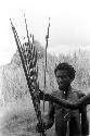 A man standing with a handful of arrows and a bow near Homoak